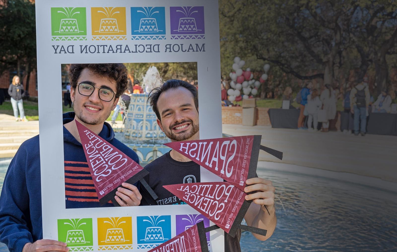 Blaine Martin and Caleb Aguiar pose in front of the fountain with a Major Declaration Day frame