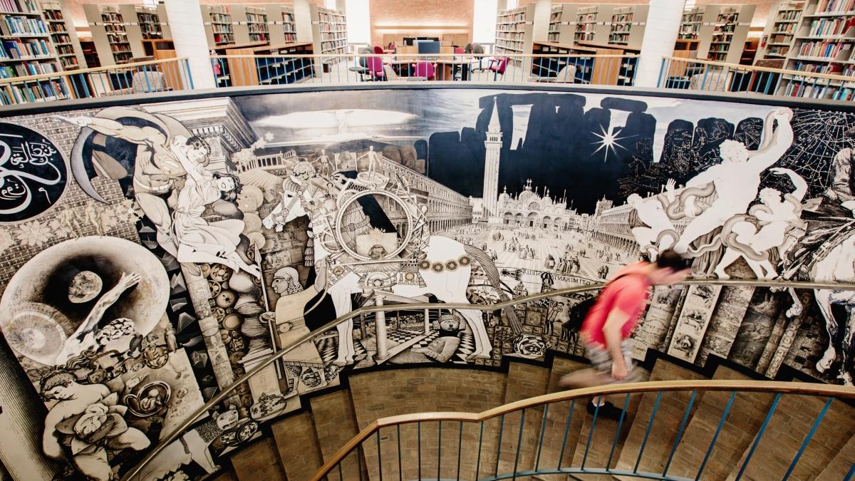 Student climbs spiral stairwell decorated with a mural in Coates 图书馆